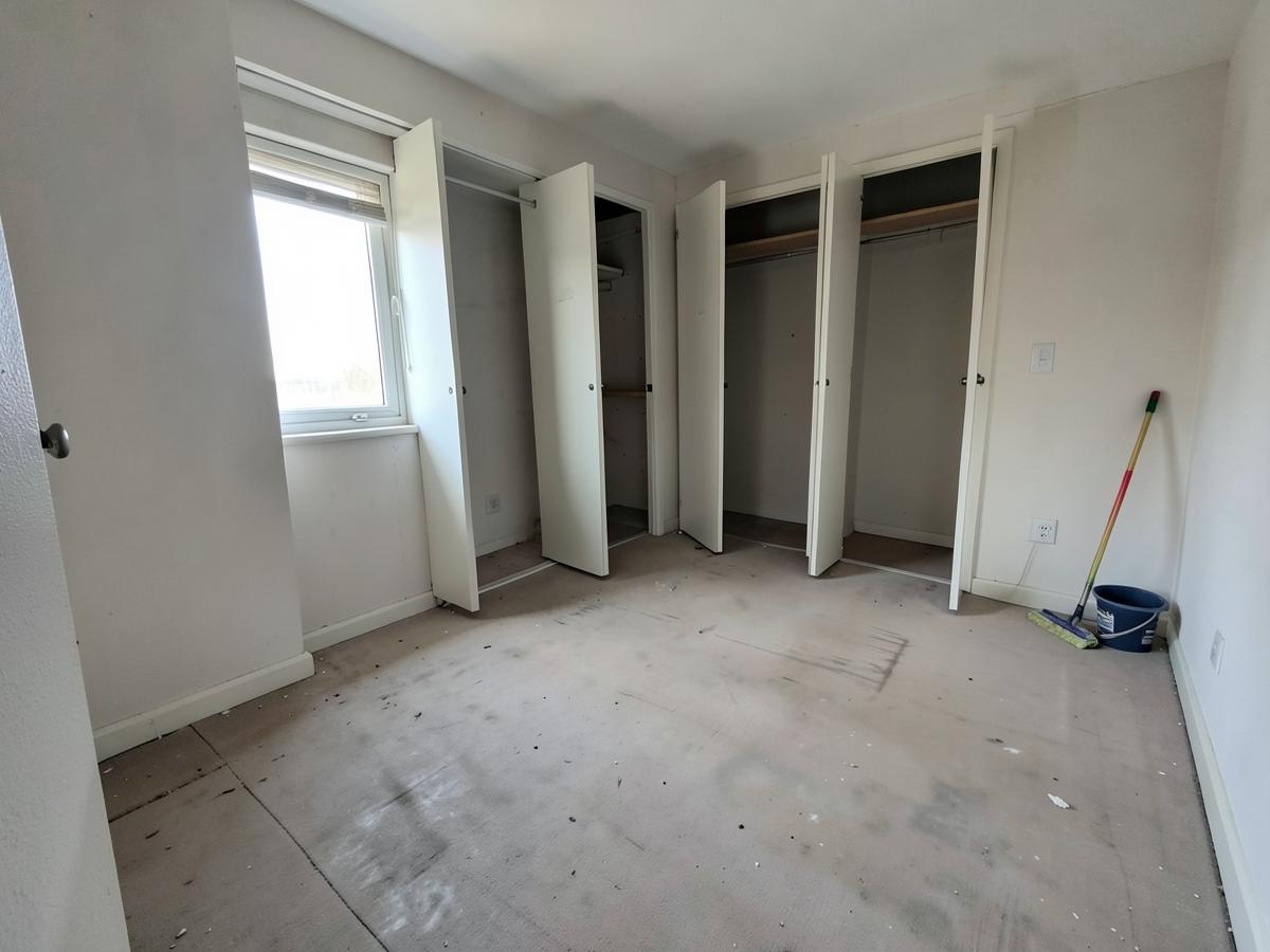 Vacated bedroom with empty closets and cleaning equipment ready for a move-out clean