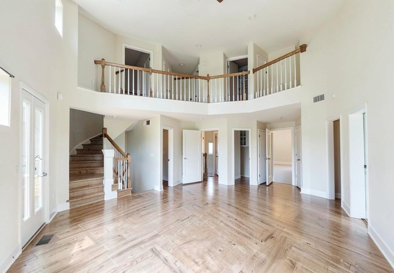 Wide empty home interior with staircase and multiple doorways